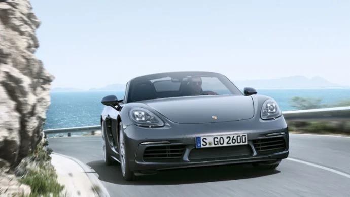 Front view of an Agate Grey Porsche 718 Boxster on a coastal road